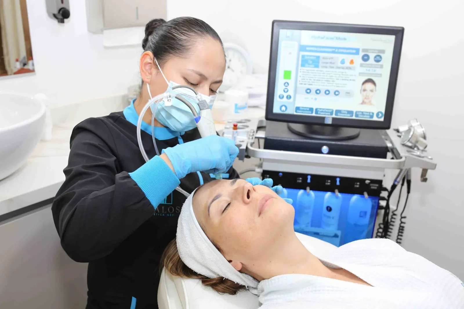 Profesional de Kalos aplicando Hydrafacial a una paciente en cabina
